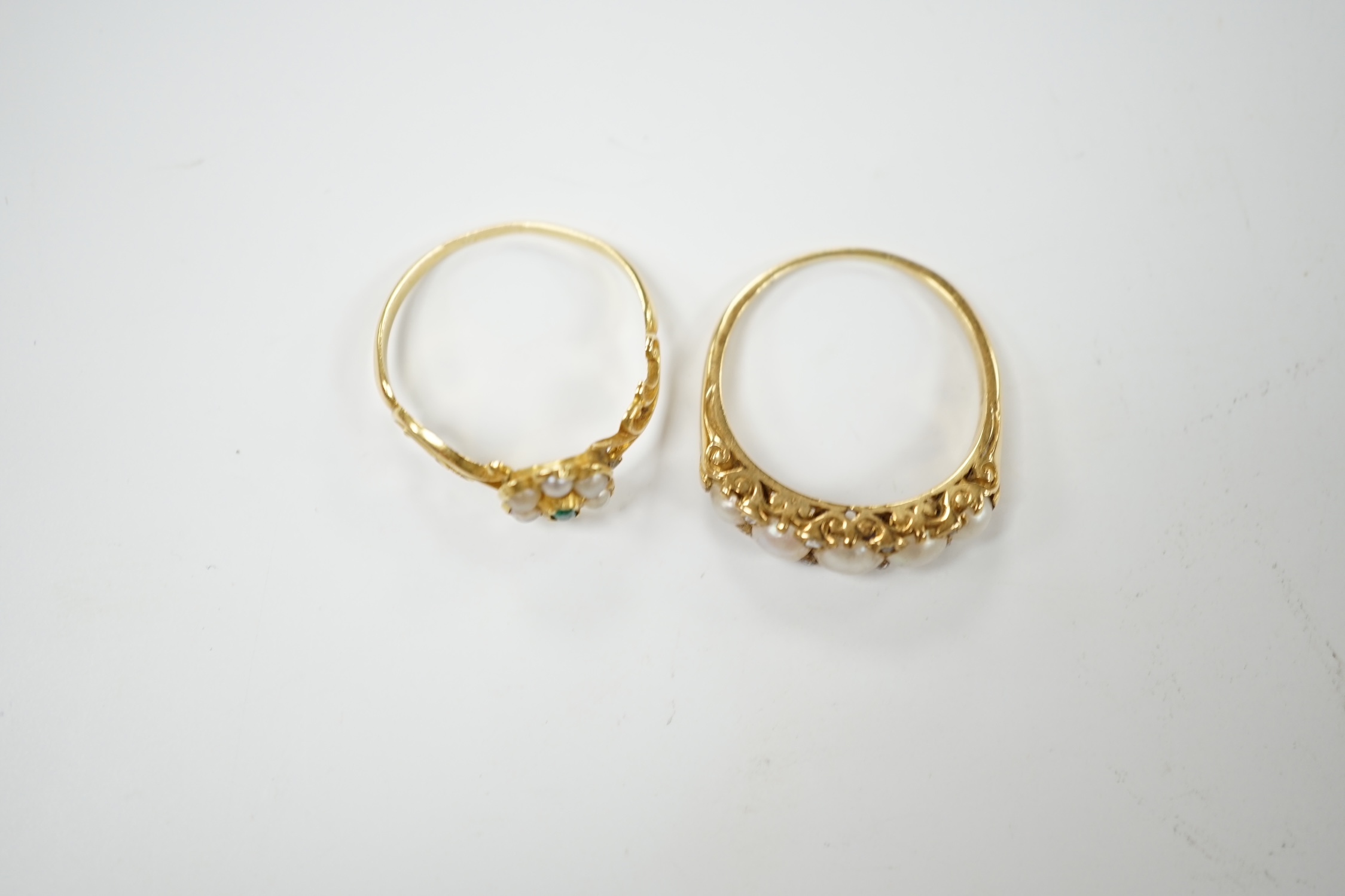 A yellow metal and graduated split pearl set half hoop ring with diamond chip spacers, size Q and a similar emerald and seed pearl flower head cluster ring, gross weight 5.7 grams. Condition - fair